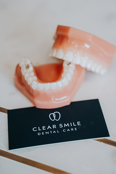 model of dentures lying next to a Clear Smile Dental Care business card
